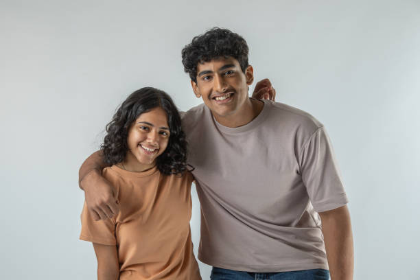 istock Happy teenage siblings standing on white background 1624676018
