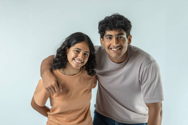 istock Happy teenage siblings standing on white background 1624677088
