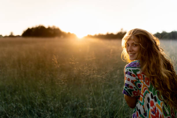 A young caucasian woman running at a field and looking  back