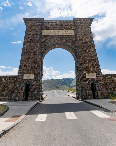 The Roosevelt Arch is a rusticated triumphal arch at the north entrance to Yellowstone National Park in Gardiner, Montana, United States. Here on a blue sky day.