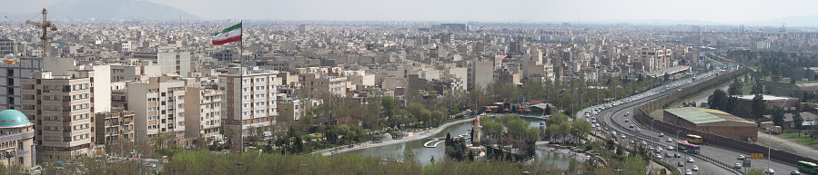 Panoramic view of The city of Tehran with the waving Iranian Flag