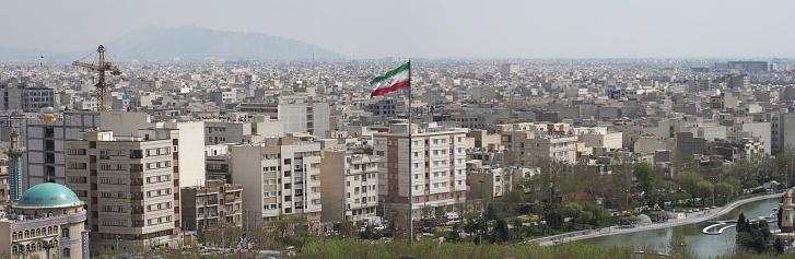 Panoramic view of The city of Tehran with the waving Iranian Flag at the center