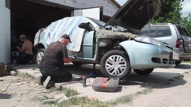 The professional auto mechanic cuts off the rusty threshold of a car.