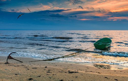 Anchored lonely fishing boat on sandy beach of the Baltic Sea