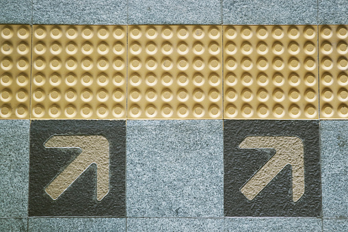 Yellow tactile paving and arrow sign of boarding direction on metro system platform