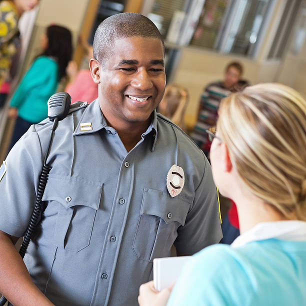 Friendly police officer talking with school teacher after safety demonstration Friendly police officer talking with school teacher after safety demonstration security guard stock pictures, royalty-free photos & images