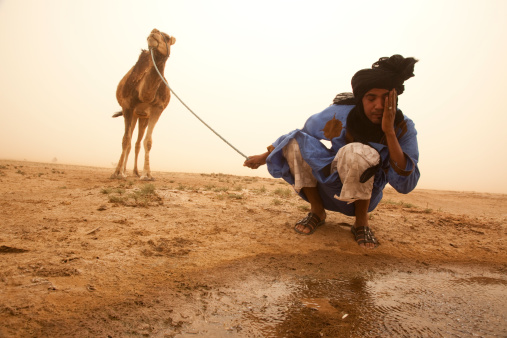 Nomadic person is washing his face on Sahara Desert, Morocco.