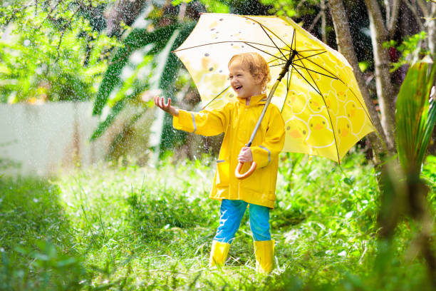 istock Child playing in the rain. Kid with umbrella. 1624941463