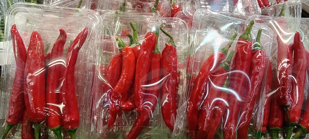 A row of fresh red chili peppers placed in the supermarket for sale to buyers
