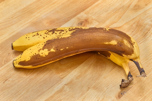 A bunch of very ripe bananas on a wooden counter in the kitchen