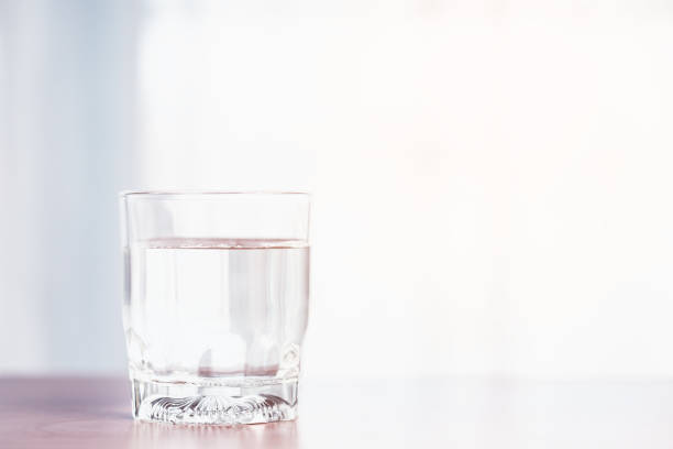 istock A clear glass containing water is placed upon a wooden table with soft orange sunlight from outside for the concept of healthy water consumption. 1624985183
