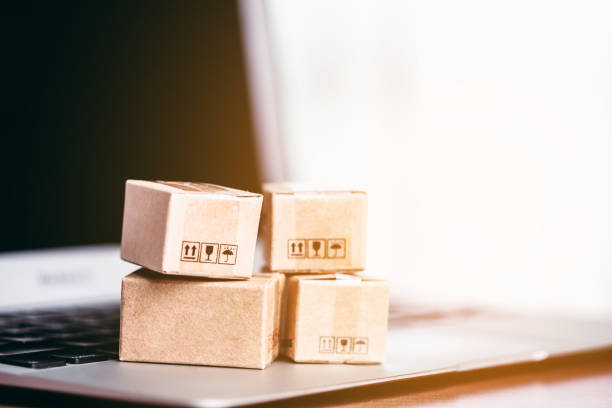 istock Brown parcel boxes are arranged on a laptop with a soft, gentle orange sunlight from the outside for the concept of online shopping, convenience and purchases arriving at doorstep. 1624985185