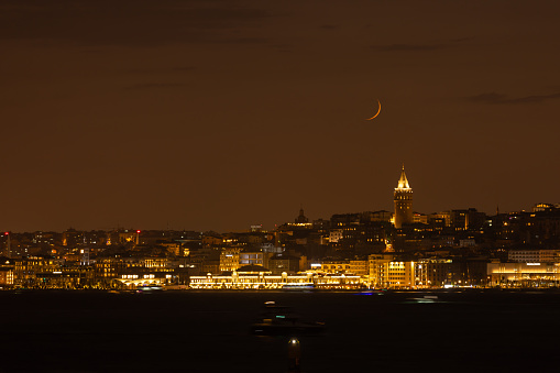 The crescent-shaped moon sets over the Galata tower.\nIstanbul - Turkey.