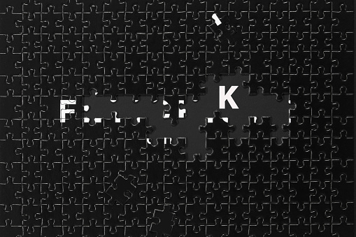 Fragment of a folded black puzzles on a black background with letters 