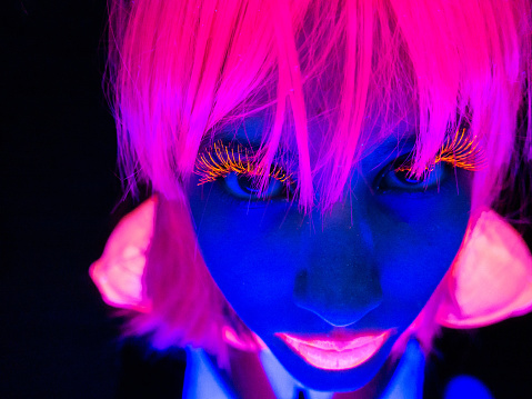 Portrait of a young woman under UV lights, looking up