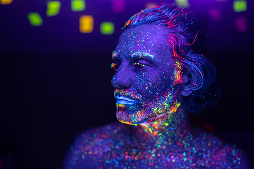 Male portrait painted with fluorescent colours under UV lights