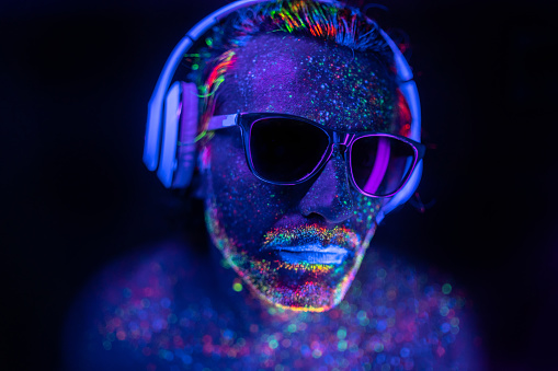 Male DJ with headphones under UV lights