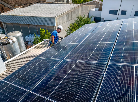 Electrical engineer latin american man checking solar photovoltaic panels on the roof of a solar farm.
