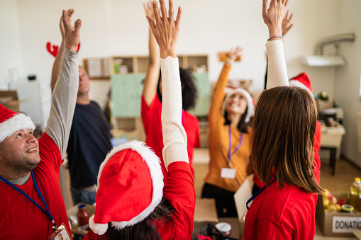 With one arm raised in the air, a group of aid workers are all volunteering their time, wearing red t-shirts and Santa hats