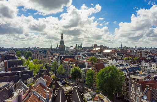 Beautiful Amsterdam Cityscape from Aerial rooftop perspective above Canals and Church Tower View with Blue Sky and big clouds HQ