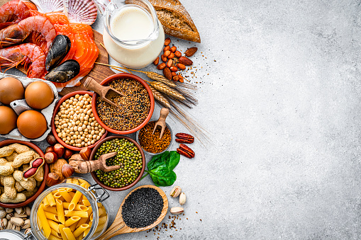 Most common allergens food shot from above. The composition includes fish, crustaceans mussels, peanut, eggs, milk soy products, bee pollen, nuts, wheat and derivates and sesame. The composition is at the left of an horizontal frame leaving useful copy space for text and/or logo at the right.  High resolution 42Mp studio digital capture taken with SONY A7rII and Zeiss Batis 40mm F2.0 CF lens