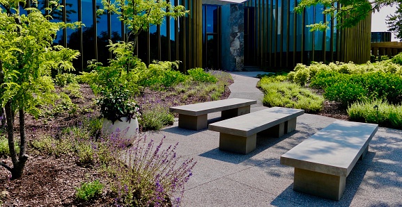 Tom Patterson Theatre, Stratford ON - unique cement patio benches in lush foliage at the front of the building - profile view\n\nLocation\nStratford ON CA