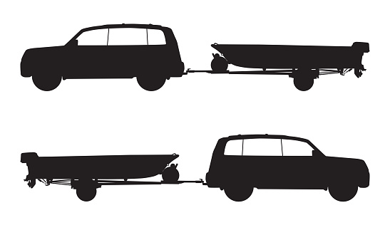 A sport utility vehicle is pulling a boat on a trailer in silhouette