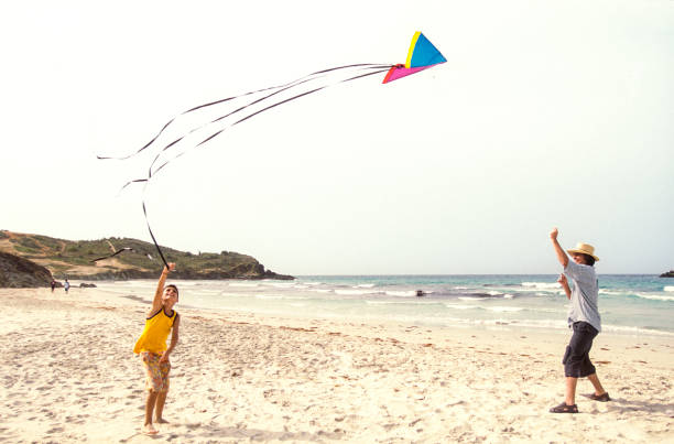 large butterfly kite flying above the sea while a young girl stands quietly at the shoreline. A poetic and nostalgic scene of childhood captured in black and white. Solitude and gen alpha concept.