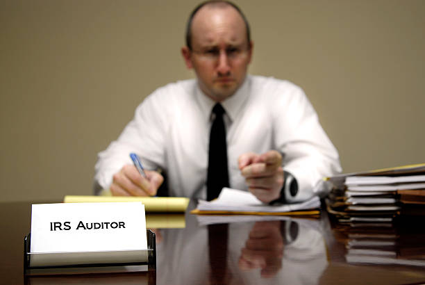 A male IRS tax auditor at a desk with paperwork stock photo