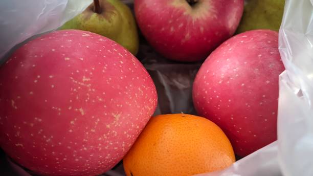 istock Apples, oranges and green pears in clear white plastic 1625245617
