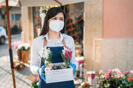 Young woman arranging her flower shop for opening after Coronavirus Pandemic.