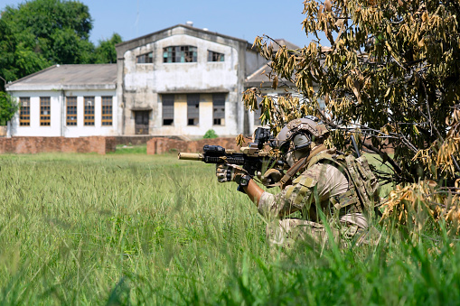 A close up on a modern machine gun with a scope used by the military in war scenarios seen in the middle of a dry field on a sunny summer day during a military fair