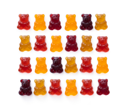 Fruit flavored gummy bears, in a row, isolated on white background