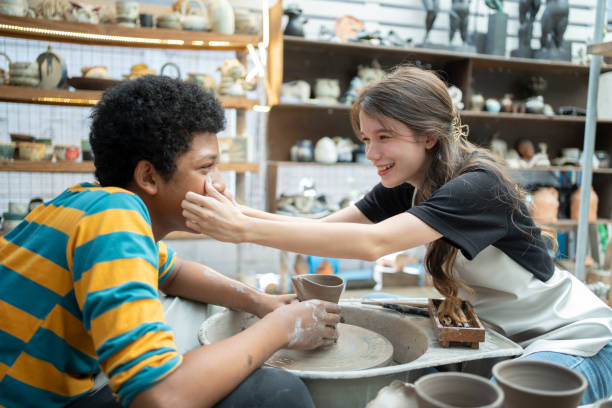 Senior adult making ceramics in her workshop with her granddaughter working grandparents and small business concept