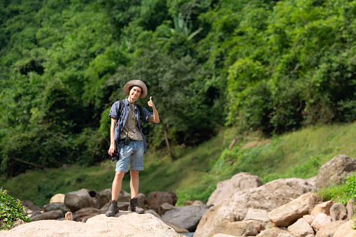 Young man with backpack hiking in the forest. Active lifestyle concept.