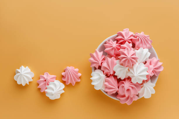 istock Pink and white meringues on an orange background 1625323968