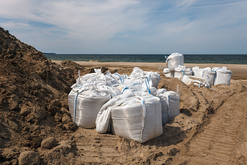 Large white bags made of synthetic fabric filled with sand to strengthen the shore