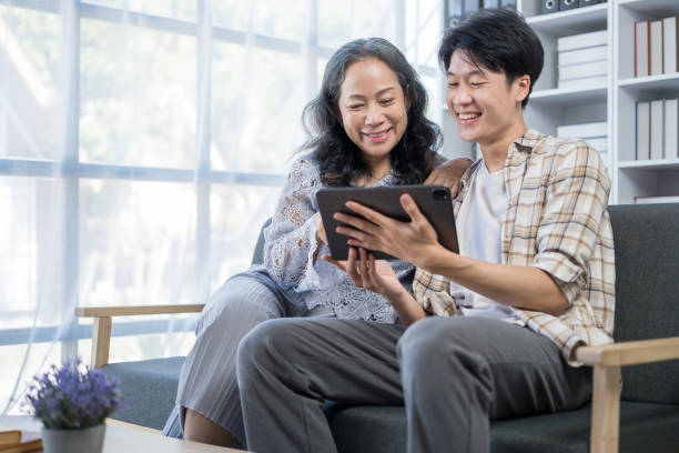 istock Overjoyed middle age mother and son having fun with digital tablet, watching funny video, shopping online. 1625336374
