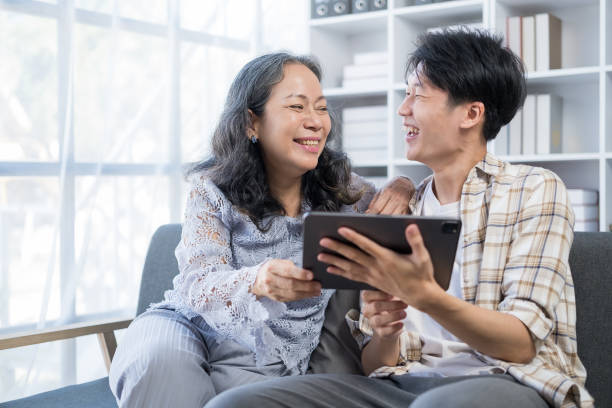istock Smiling young man teaching elderly mother using digital tablet at home. People, technology and family. 1625336381