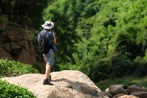 Young man with backpack hiking in the forest. Active lifestyle concept.