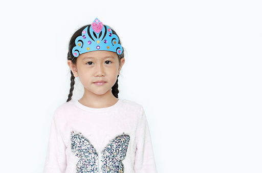 Portrait of little Asian child girl with wearing a crown toys isolated over white background.