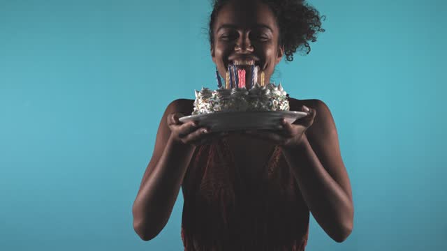 Young woman contemplating her wish after blowing out candles on a birthday cake