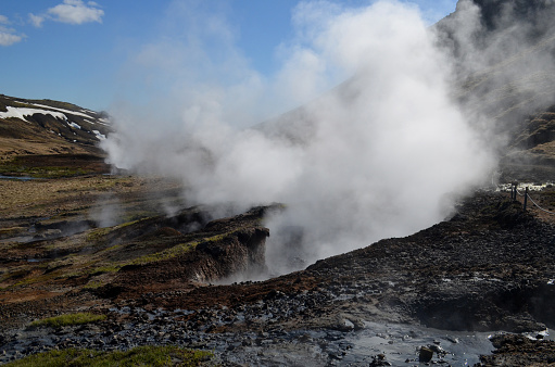 Billowing hot steam rising out of fumaroles in rural rugged Iceland landscape.