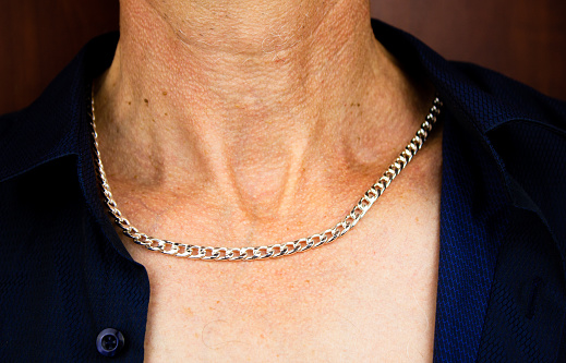 Man in an unbuttoned shirt with a silver chain around his neck. Men's jewelry, silver chain.