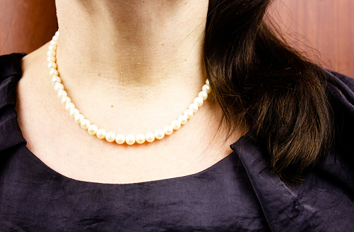 Woman with a white pearl necklace.Woman with white round beads.Women's jewelry white round beads,necklace around her neck.