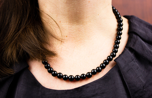 Black necklace on a woman. Women's black jewelry. Round black beads on a woman.