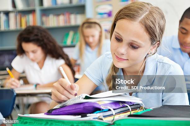 Young Student Writing In Class Full Of Students Stock Photo - Download Image Now - Adolescence, African Ethnicity, American Culture