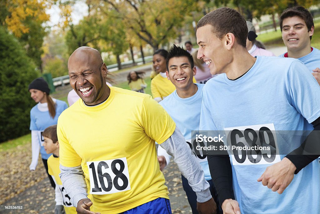 Homens em uma instituição de caridade corrida rindo juntos - Foto de stock de Festa beneficente royalty-free