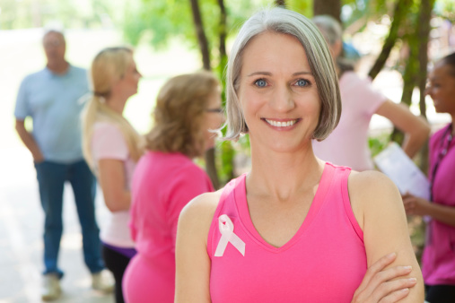 Smiling woman with ribbon at a breast cancer charity event. 