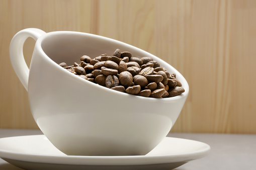 Coffee concepts. Coffee beans in a coffee cup on the wooden background with copy space